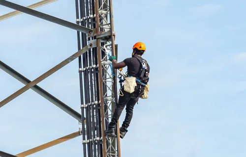 Workman doing maintenance on energy distribution tower